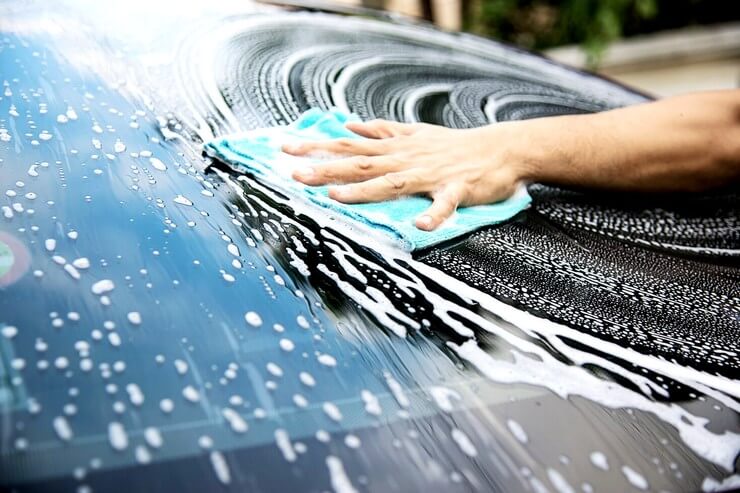 L'homme lave la voiture avec du shampooing