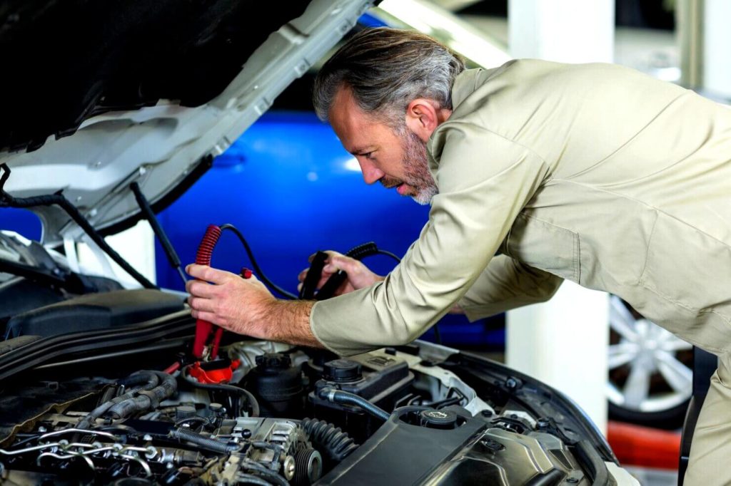 Mécanicien qui charge la batterie de voiture