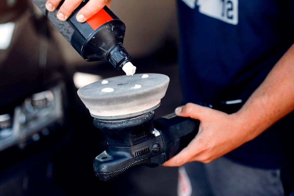 Un homme polie une voiture dans un garage