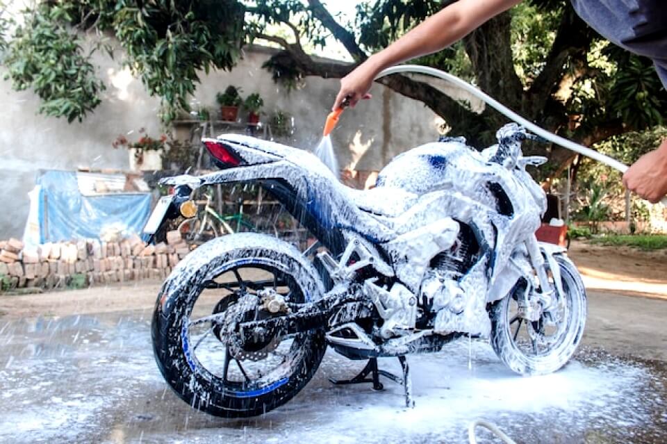 Homme lavant sa moto avec du savon