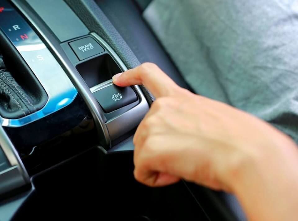 Main en poussant le frein à main électrique d'une voiture