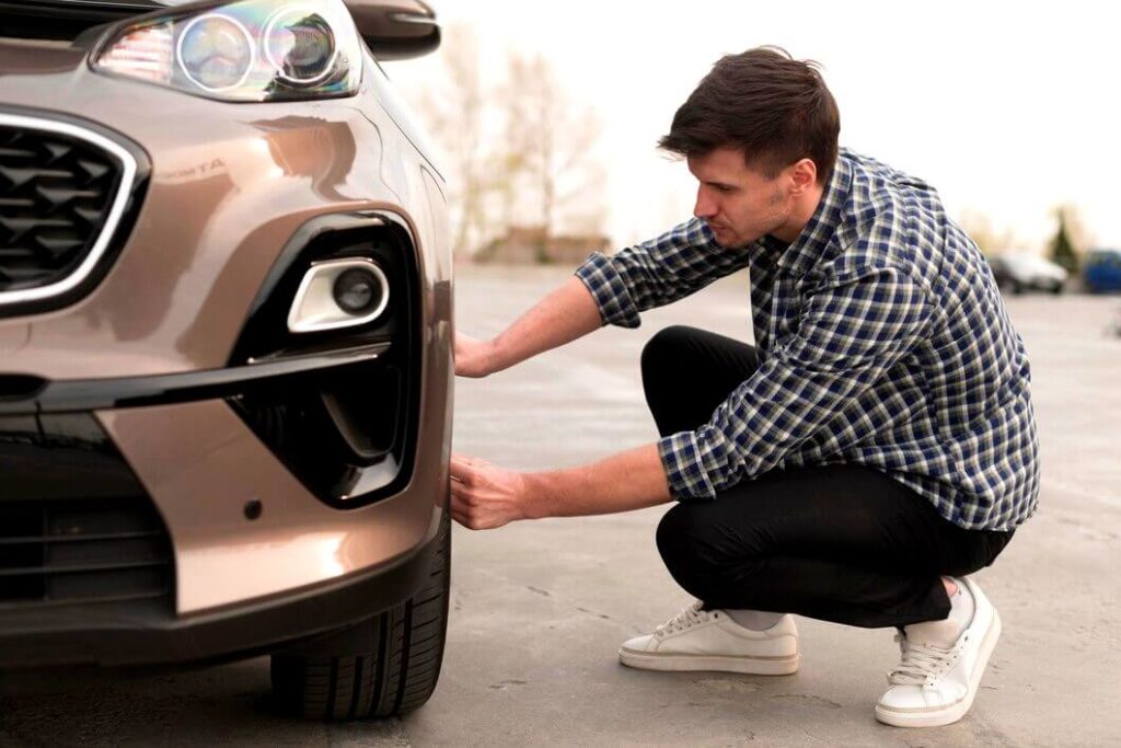 Jeune homme inspecte les freins de sa voiture