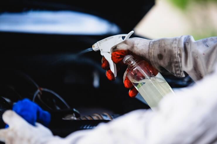 Travailleur vaporise le moteur d'une voiture