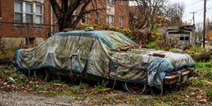 une voiture avec un bache en stationnement depuis longtemps