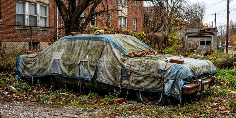 une voiture avec un bache en stationnement depuis longtemps